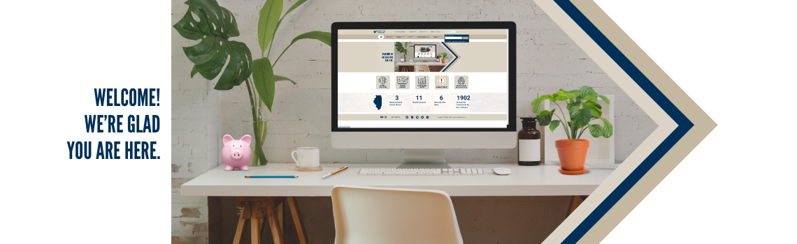 A modern desk setup with a computer displaying the Bank & Trust Company website. The desk features a potted plant, a pink piggy bank, a coffee cup, and various office supplies. The text on the left reads 'Welcome! We are glad you are here.'