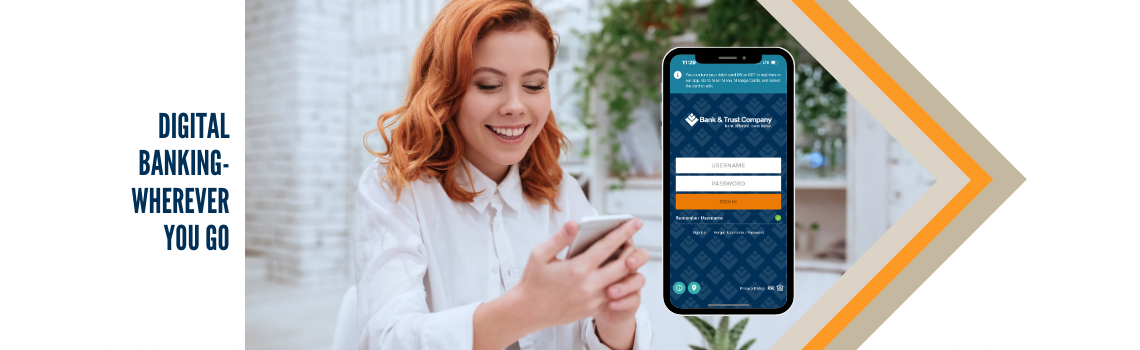 "A smiling woman with red hair using her smartphone for digital banking. A large smartphone screen on the right displays the Bank & Trust Company mobile app. Text on the left reads 'Digital banking - wherever you go.'"