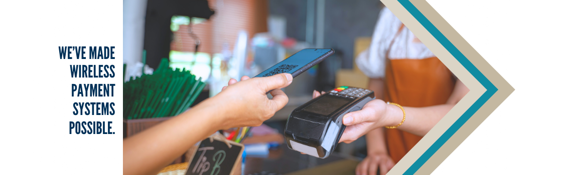 Close-up of a customer making a wireless payment using a smartphone at a retail counter, with a payment terminal held by the cashier. Text on the left reads 'We've Made Wireless Payment Systems Possible.'"