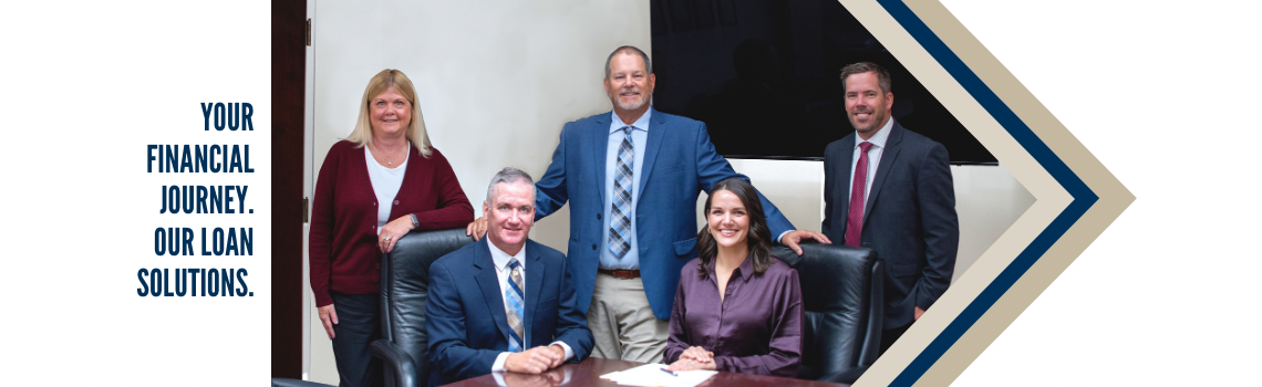 "A group of five professional employees, including Daniel Fleming, posing together in a conference room. Text on the left reads 'Your financial journey. Our loan solutions.'"